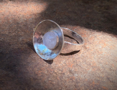 Silver ring with a clear stone on a textured surface